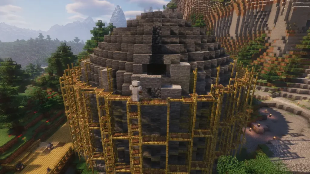 A large stone dome under construction in Minecraft Survival Mode, surrounded by bamboo scaffolding in a mountain biome, with a player wearing iron armor placing stone blocks during daytime.